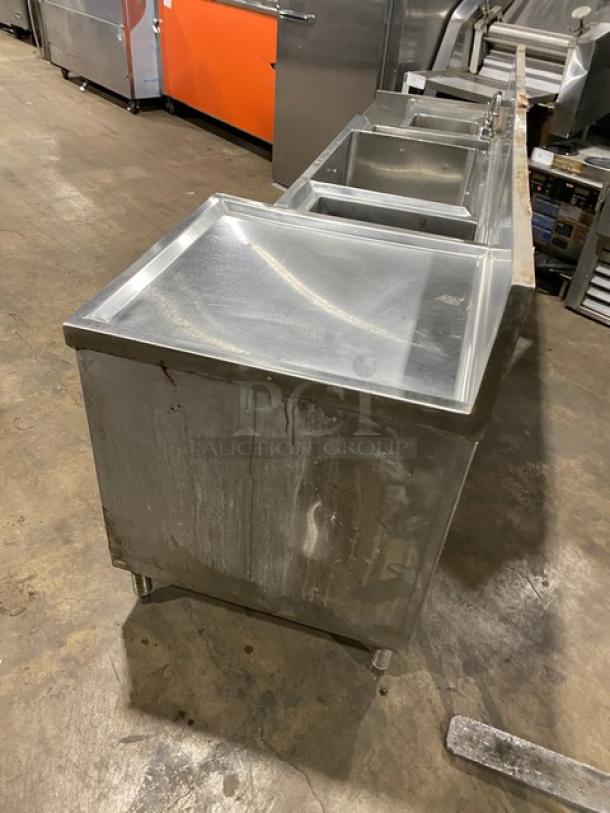 Commercial stainless steel cocktail station with backsplash, integrated dump sink, swivel faucet, ice bin, speed rail, on legs.