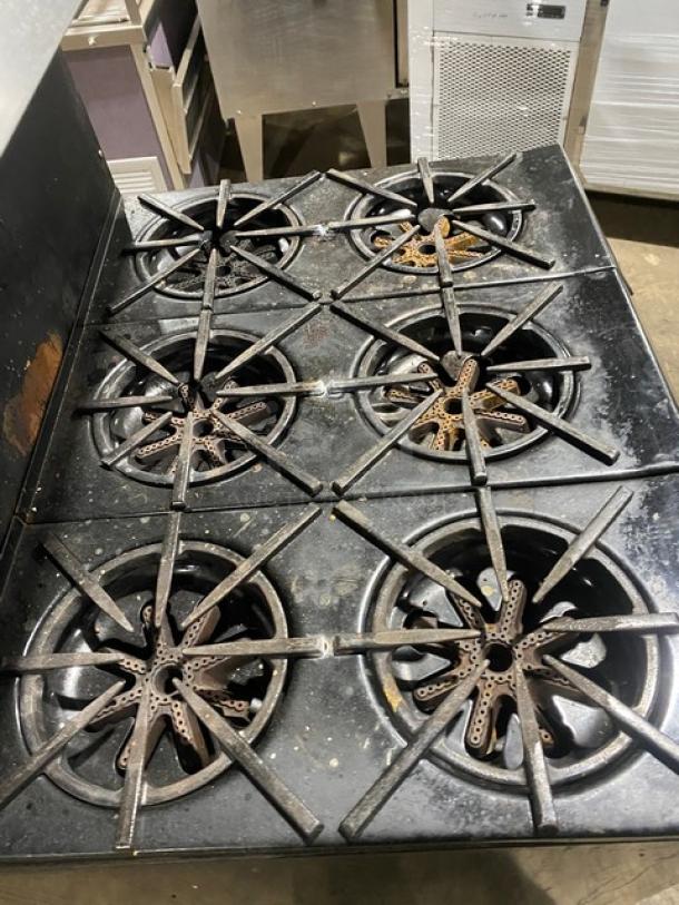 Garland stainless steel 6-burner gas range with backsplash, overhead salamander shelf, and wired oven rack. Used condition.