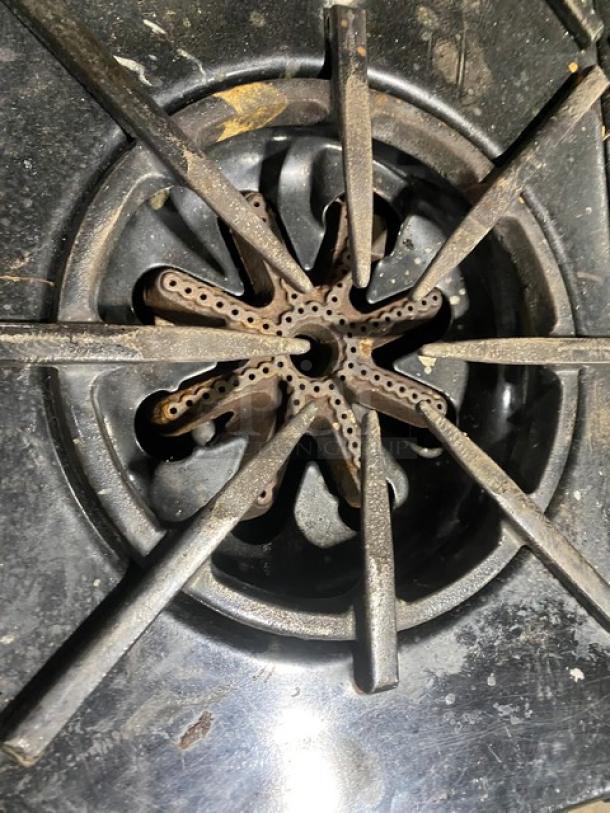 Garland stainless steel gas range stove burner, well-used with visible wear, part of a 6-burner range/oven combo.