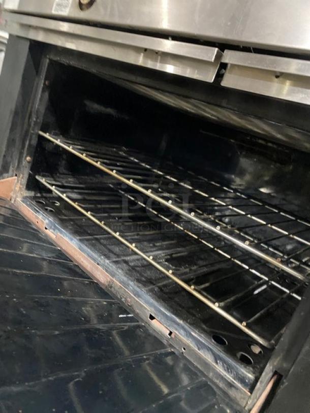 Garland commercial stainless steel gas range with 6 burners, oven, backsplash, overhead salamander shelf, and wired rack.