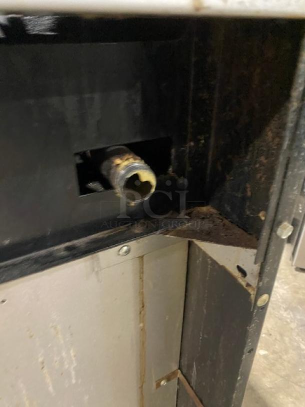 Garland commercial stainless steel gas-powered 6-burner range/oven combo bottom view, showing rust and wear on internal components.