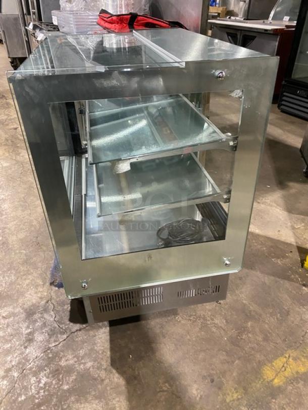 Commercial stainless steel refrigerated bakery display case with straight glass, multi-tier shelves, and rear access sliding doors.