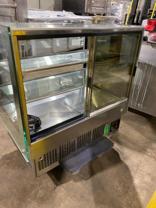 Commercial stainless steel multi-tier refrigerated bakery display case with straight glass, rear access double sliding doors.
