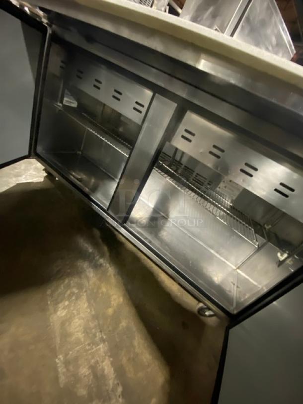 Turbo Air TST60SD24N refrigerated prep table, stainless steel, 2-door, with cutting board and chrome rack, on casters.