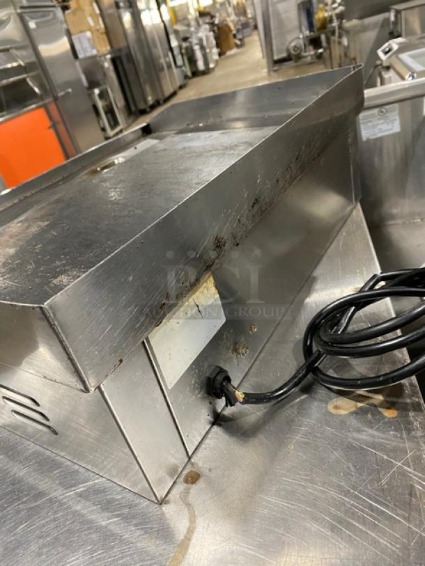 Commercial stainless steel electric griddle with back and side splash, countertop model, used condition, visible power cord.