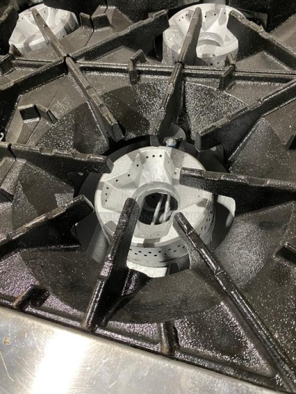 Radiance 6-burner gas range detail showing sturdy stainless steel grates. Pristine condition, ideal for commercial kitchens.