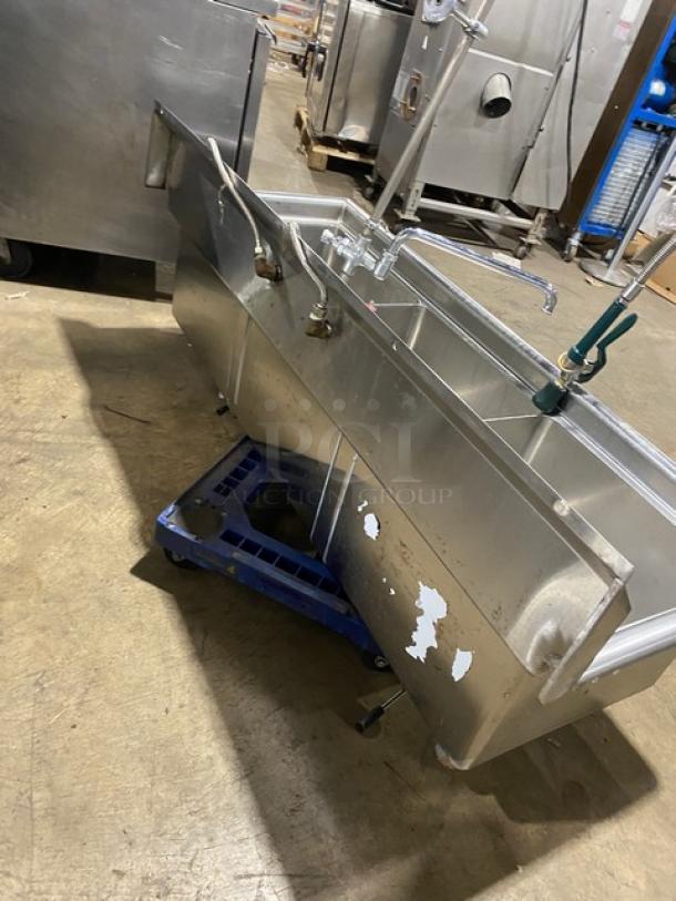 Commercial stainless steel 3-compartment dishwashing sink with backsplash, swivel faucet, jet spray attachment, and legs. Some surface wear.