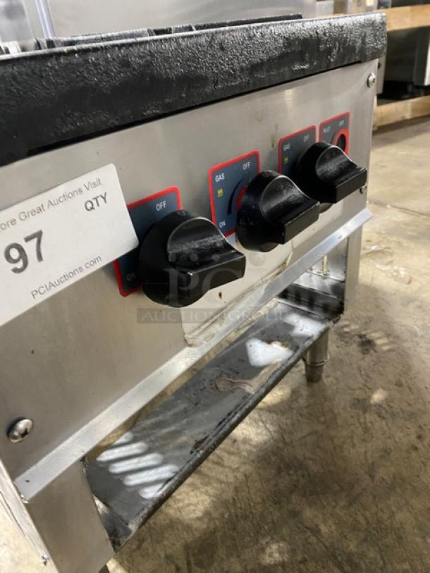 Commercial stainless steel gas-powered single burner stock pot range on legs, featuring control knobs and visible wear.