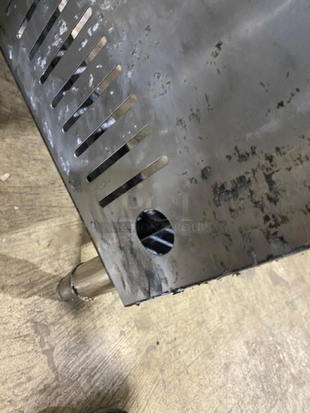 Commercial stainless steel gas-powered single burner stock pot range with sturdy legs. Signs of wear shown; ideal for professional kitchens.