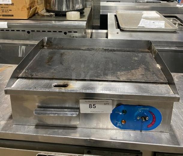 Commercial stainless steel countertop electric griddle with back and side splash, visible temperature controls; shows moderate wear.