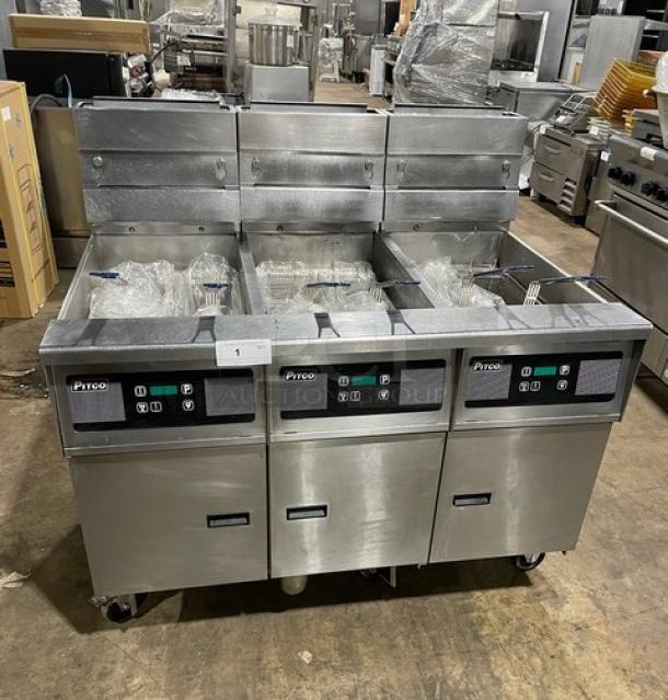 Pitco SG14-JS stainless steel 40 lb. triple-bay fryer system with digital control, backsplash, basket hanger, and caster wheels.