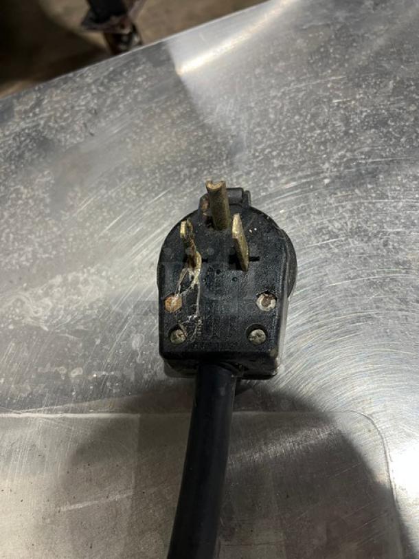 Close-up of an electric plug for the Market Forge PS3E commercial steamer, showing moderate wear and grime on a stainless surface.