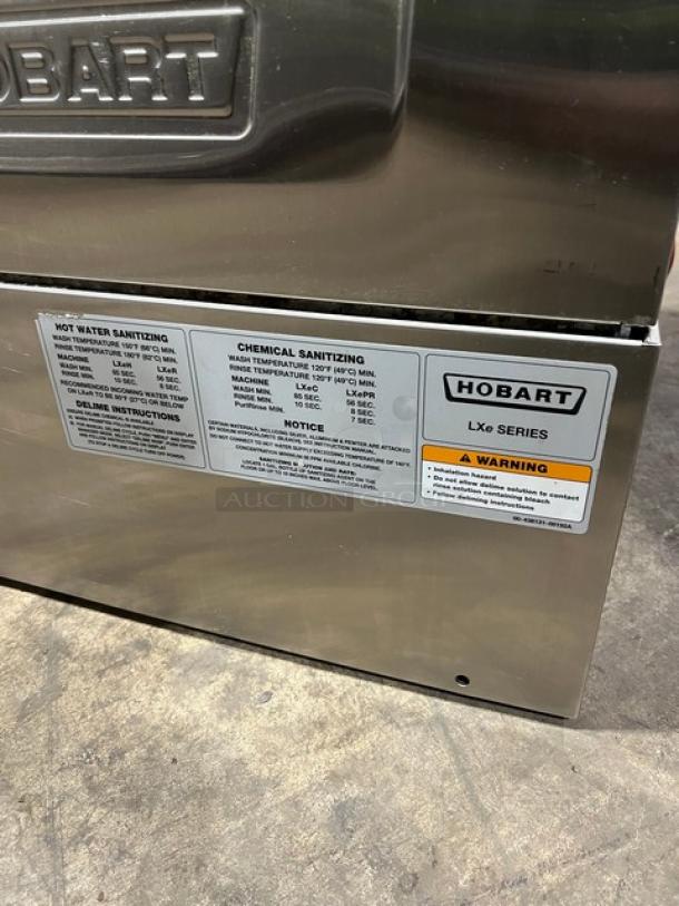 Hobart LXe Series stainless steel undercounter dishwasher, Energy Star certified. Features visible instructions and safety warnings.