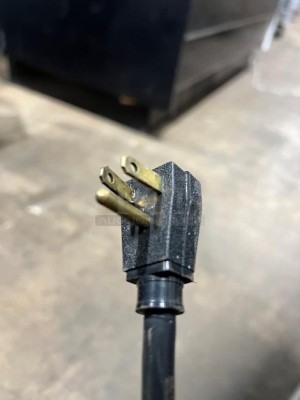 Close-up of a three-prong cord plug for a True T-23F stainless steel reach-in freezer.