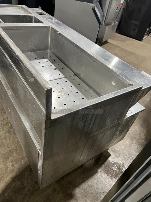 Custom commercial stainless steel triple bar station with backsplash, integrated ice bin, sink, and drain board on legs.