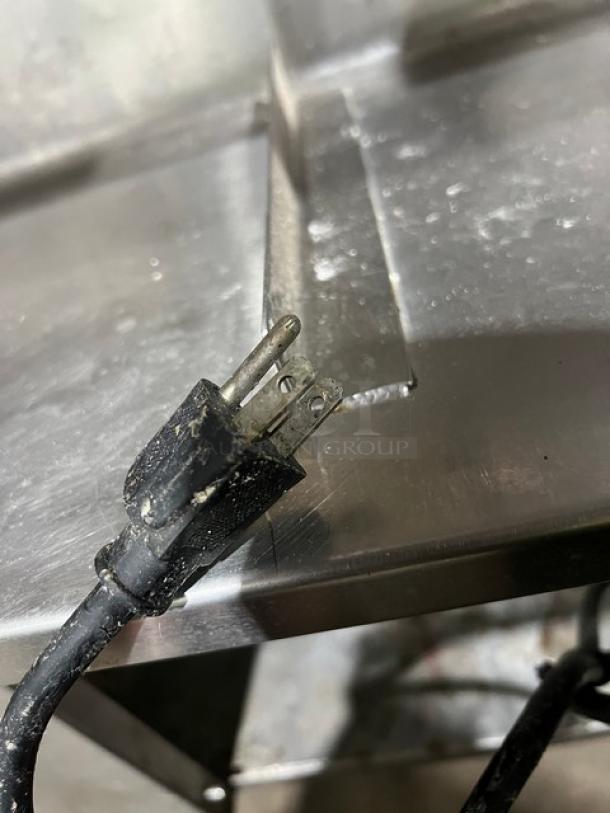 Custom stainless steel bar station with single drawer, ice bin, sink, and drain board. Features backsplash and legs, visible plug.