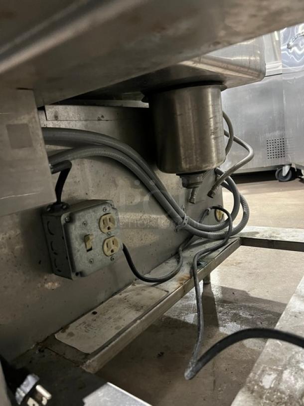 Custom stainless steel bar station with single drawer, ice bin, sink with drain board, and backsplash on legs.