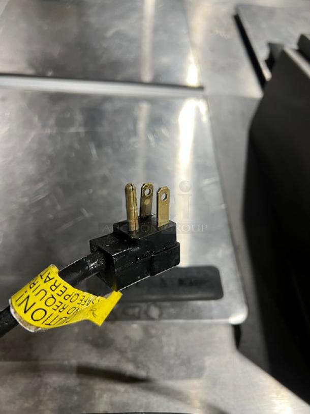 Master-Bilt FLR60 Ice Cream Topping Unit power cord plug, showing three-prong connection and caution tag.