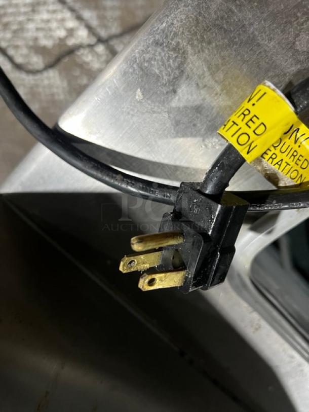 Close-up view of a power plug with a yellow tag on a Master-Bilt FLR-60 ice cream topping unit, emphasizing electrical details.