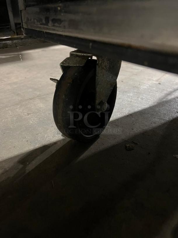 Close-up of a caster wheel on a True commercial stainless steel 2-door refrigerated prep table, model TSSU-60-24M-B-ST-HC.