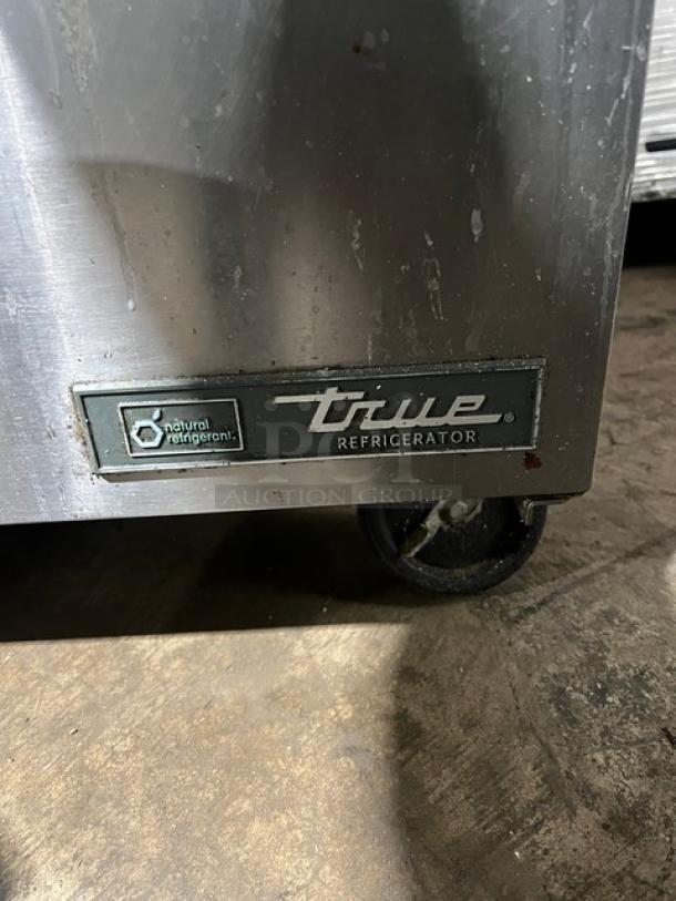 True TSSU-60-24M-B-ST-HC refrigerated prep table, commercial stainless steel, two-door, with wired racks, on casters.