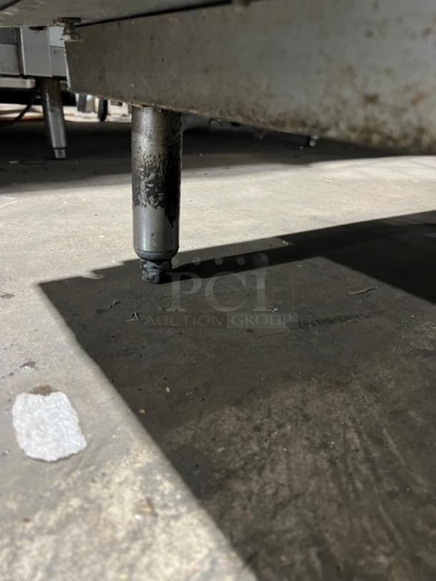 Commercial stainless steel pizza prep table leg, model 51268AM, serial W00000028197, on durable legs with visible wear.