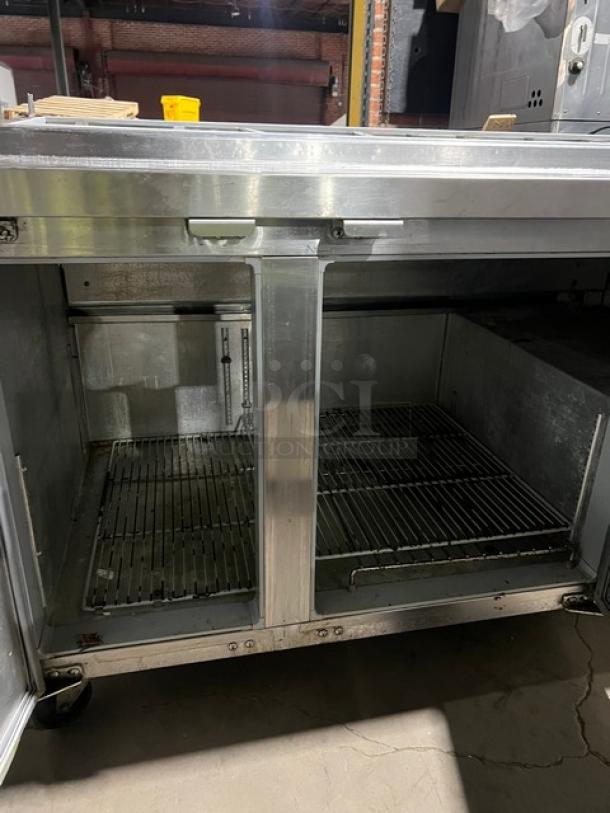 Continental CPA60 stainless steel refrigerated pizza prep table with wired rack, SN 155C1556, 115V, 1 phase, on casters.