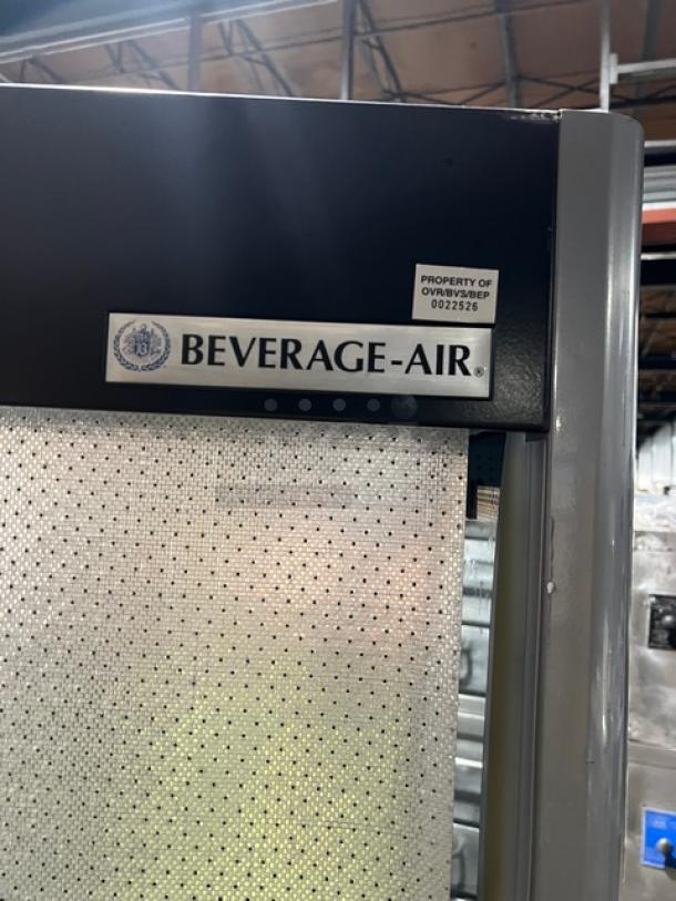 Beverage-Air VM18 Multi-Tier Refrigerated Merchandiser with pull-down night curtain and adjustable shelves, featuring branding label.