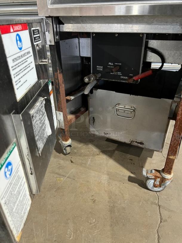 BKI 2015 commercial stainless steel electric pressure fryer, model LPFF. Features color-keyed locking spindle, lid-lock system, 208V 3-phase, on casters. Visible usage wear.