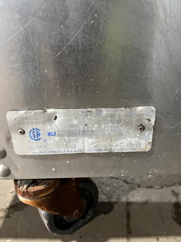 Garland CXBE12 stainless steel hamburger press with wavy grates, electric-powered, 208V 3-phase, on casters, label visible.