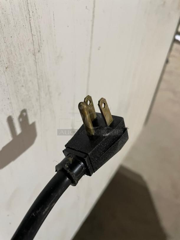 Close-up of a power plug connected to the True GDM-49 merchandiser refrigerator.