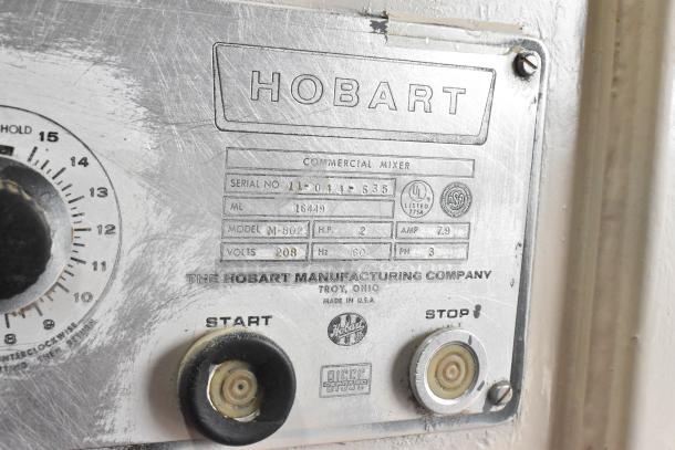 Hobart M-802 commercial mixer label with model, serial number, voltage, and brand details. Shows start/stop controls.