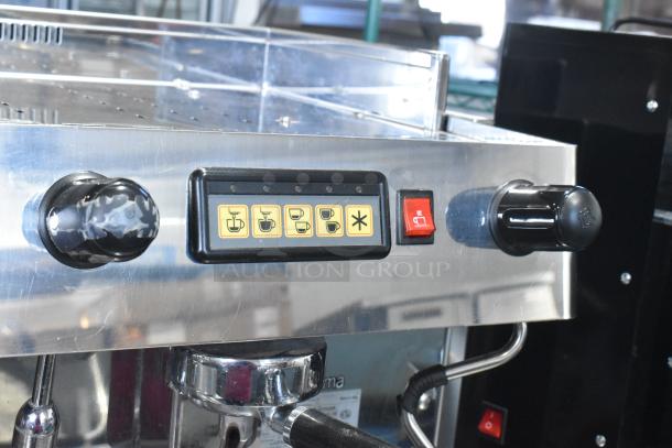 Grimac VD2GE stainless steel 2 group espresso machine with control panel, 3 portafilters, 2 steam wands, and power switch.