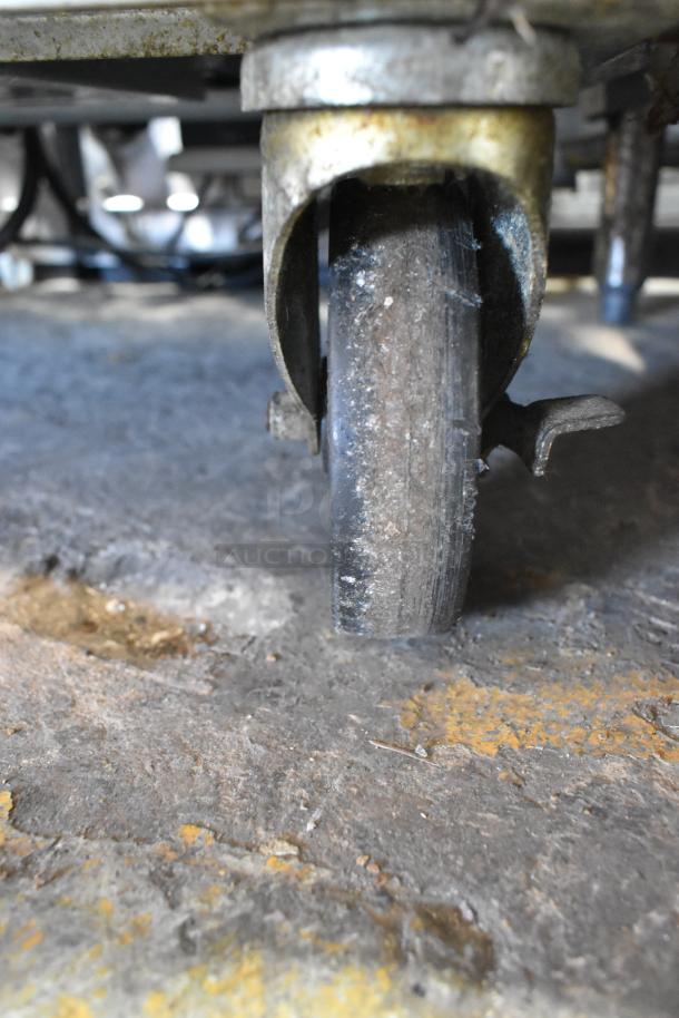 Close-up of a commercial caster wheel on a Beverage Air UCR34Y stainless steel undercounter cooler. Signs of use evident.