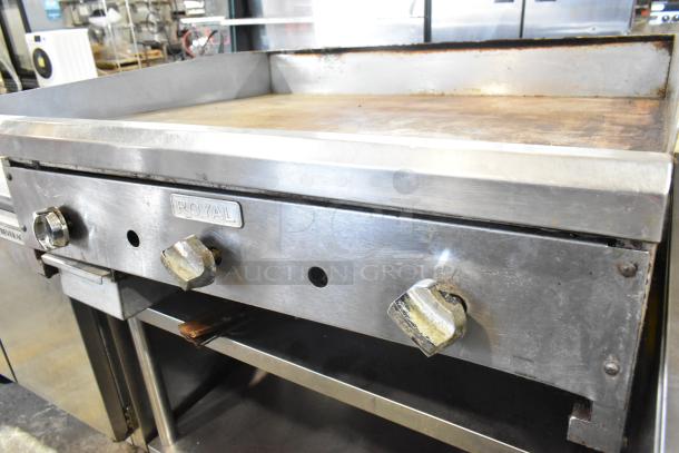 Royal stainless steel commercial gas griddle on equipment stand, featuring dial controls, showing moderate signs of use.