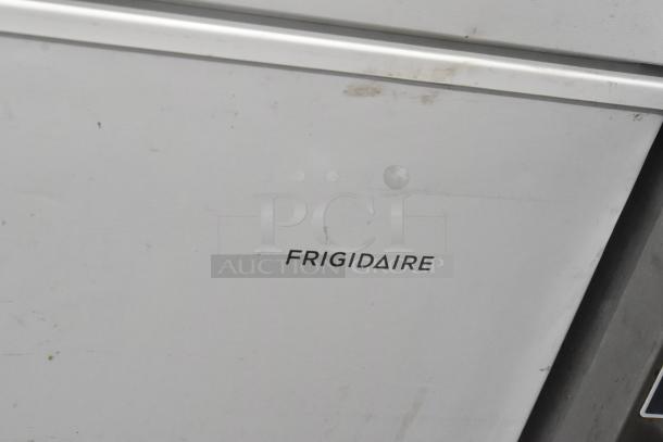 Frigidaire FFFC07M2UW chest freezer with hinge lid, metal body. Minor surface marks. 115 volts, 1 phase power. Brand visible.