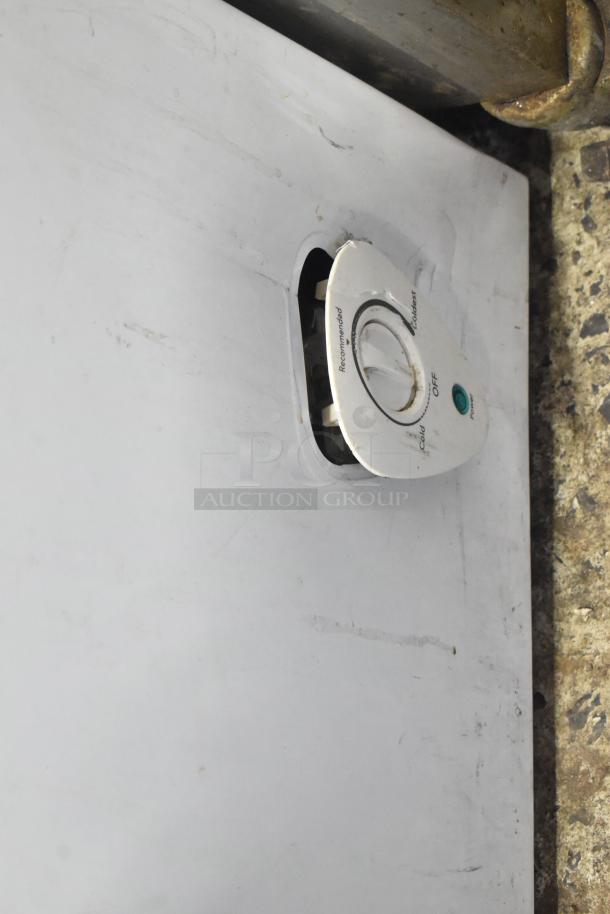 Frigidaire FFFC07M2UW chest freezer, metal body, hinge lid, temperature dial, 115V, visible wear, functional features.