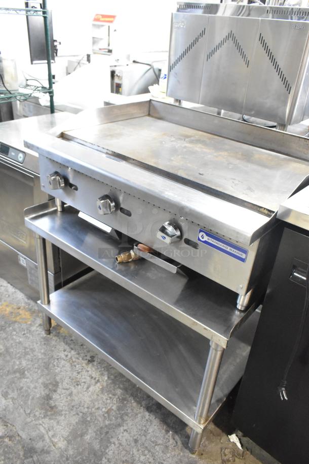 Stainless steel commercial gas flat top griddle by Standard Range on equipment stand. Features three control knobs, in good condition.