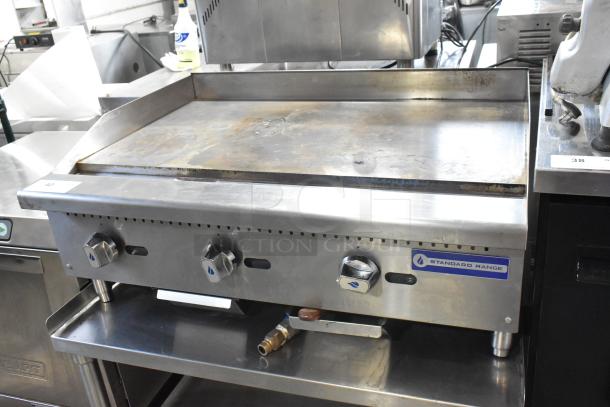 Standard Range stainless steel commercial countertop gas griddle on equipment stand, features control knobs, visible wear.