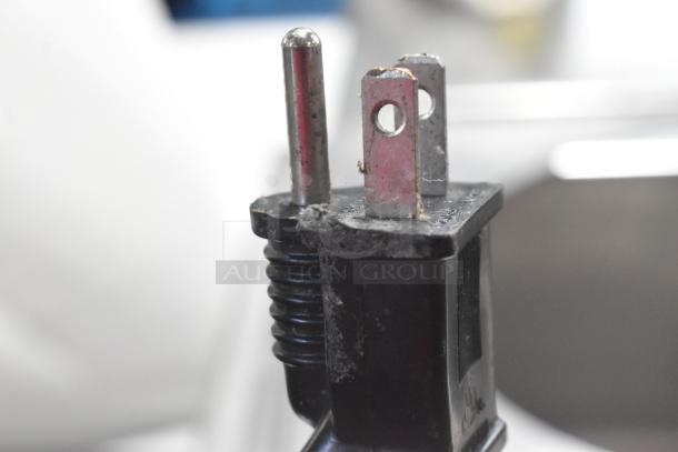 Close-up of a standard plug, showing signs of wear and dust, part of the Avantco 2022 177W50CKR food warmer.