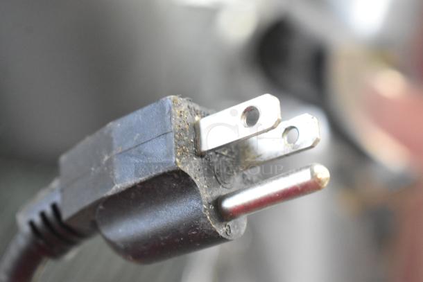 Close-up of Winco FW-S500 food warmer power plug, showing three-prong connection, minor wear on the prongs and plug body.