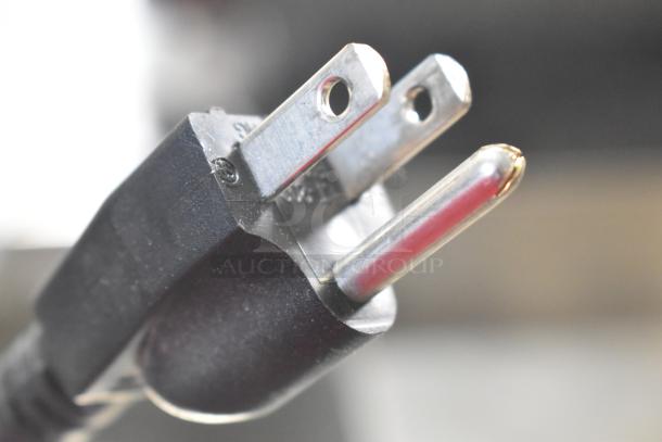 Close-up of a metal plug for Synergetic bug zappers, background blurred.