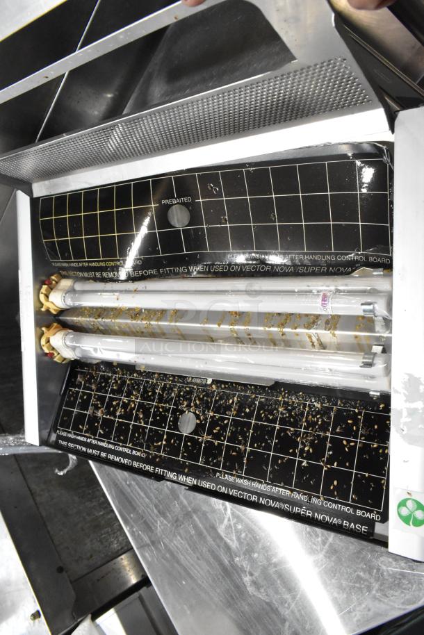 Metal bug zapper with dual fluorescent tubes, showing some residue. Operates at 115 volts, 1 phase. Markings indicate handling instructions.