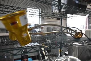 Metal 2 Head Food Warming Lamp with adjustable arms, gold finish, and perforated design. Visible label with number.