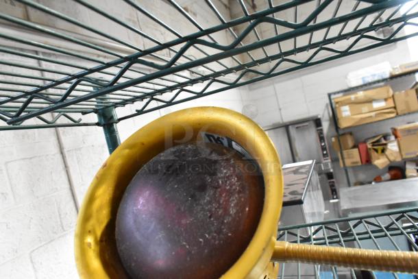 Metal 2 Head Food Warming Lamp, brass finish, used condition, visible wear marks, positioned on a metal shelf.