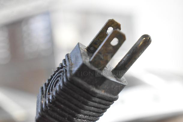 Close-up of a metal 2-prong plug from a Metal 2 Head Food Warming Lamp, showing signs of wear and use.
