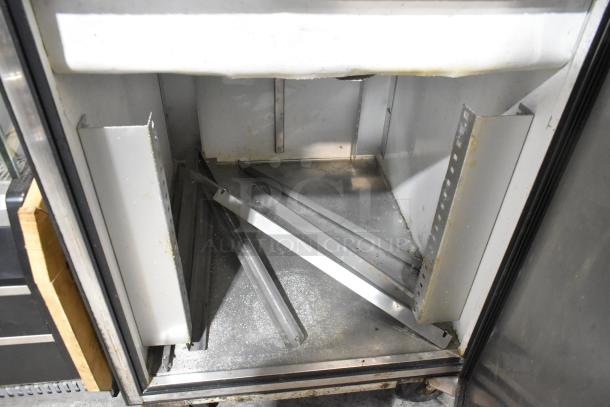 True TA1DT-2HS stainless steel reach-in cooler interior, showing commercial casters and metal shelving condition.