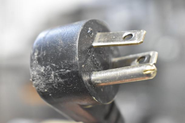 Close-up image of a black electrical plug with metal prongs, likely for the 2020 Delfield 406P-STAR2 cooler.