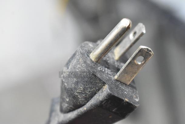 Close-up of a power plug from the Fagor CO-502W dishwasher, showing wear on metal prongs.