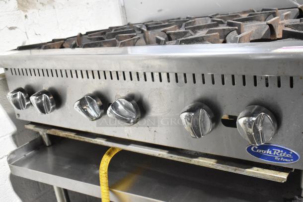 Cook Rite stainless steel 6-burner gas range on equipment stand, featuring control knobs, visible wear, and Cook Rite label.
